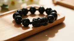 A Feng Shui Pixiu bracelet made of black obsidian beads, often worn for wealth and protection.
