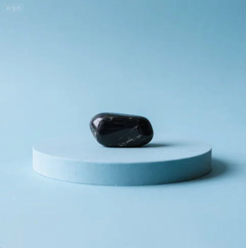 Centered black obsidian stone on a round platform with soft blue tones